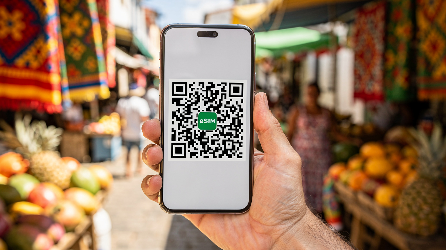 A close-up of a mobile phone screen displaying a QR code for eSIM activation, held against the backdrop of a vibrant, colorful street market in Salvador, Brazil, with blurred local vendors.